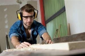 image of man cutting wood while wearing proper eye protection