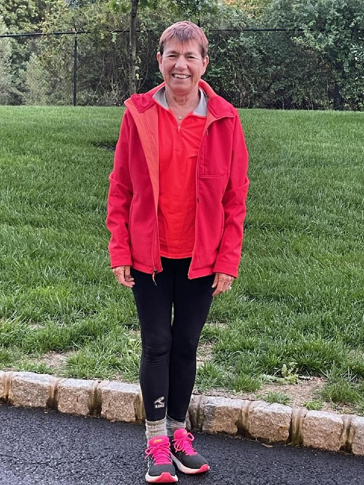 A woman standing, smiling, in exercise clothes